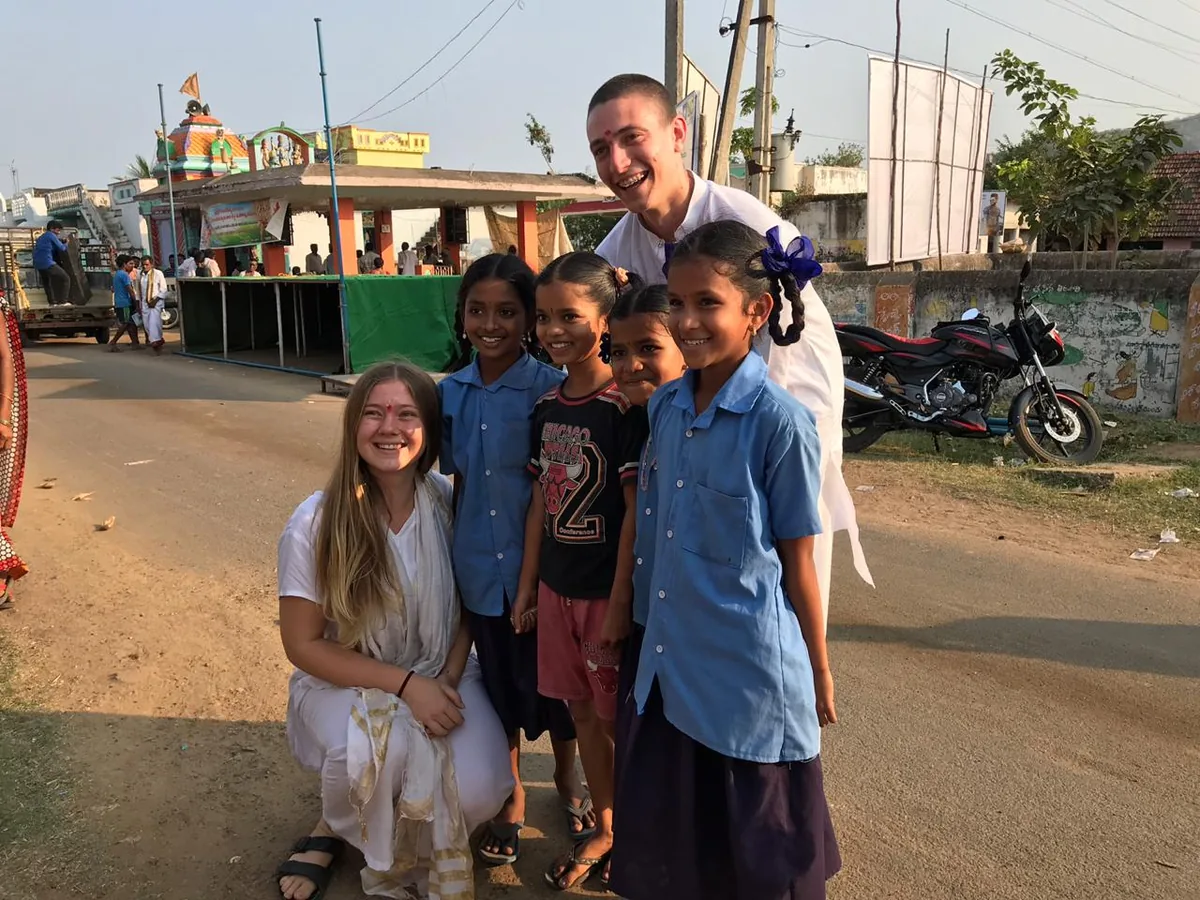 Rama en la India, sonriendo con cuatro niños en una calle de tierra